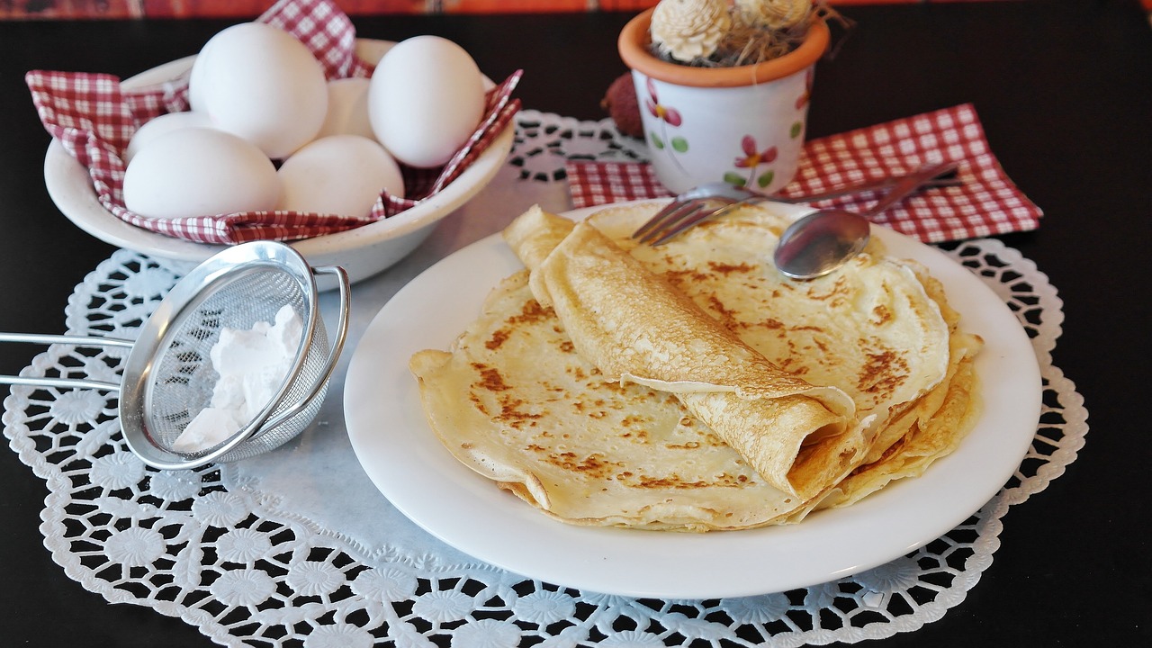 Panquques sobre una mesa y al lado de un plato con huevos.