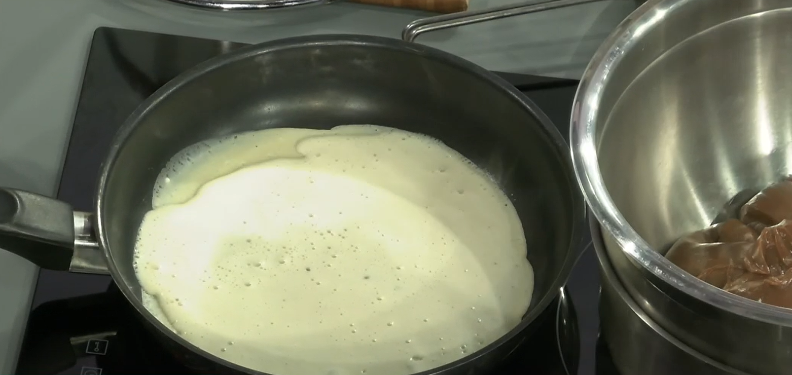 Una sarten negra con un liquido blanco en su interior.