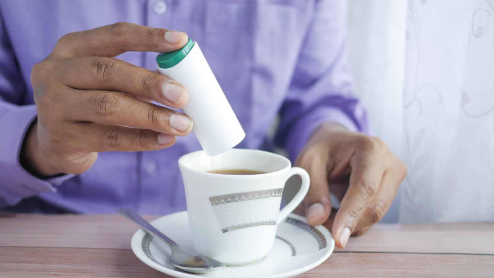 Persona endulzando un té.